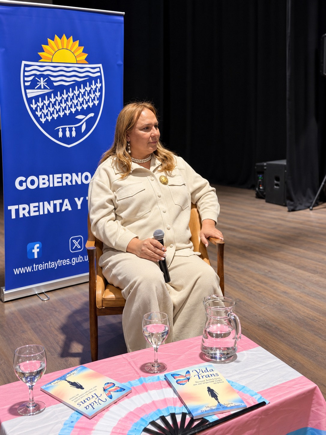 Marisol sentada con el micrófono junto a ejemplares de Vida Trans